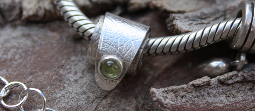 Example of work by students on this course - silver charm set with peridot